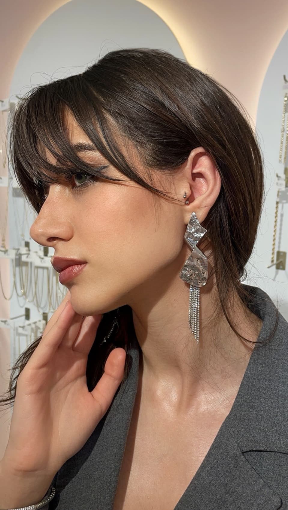 İlora gümüş şelale küpe takan model — atölyenin kemerli önünde