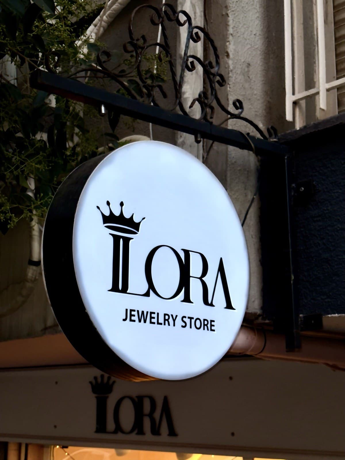 İlora Jewelry Store'un sokaktaki yuvarlak, taçlı tabelası